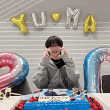 a person sitting in front of a cake that says happy birthday yuma on it