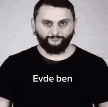 a man with a beard is wearing a black t-shirt with the words evde ben on it .