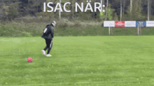 a man kicking a soccer ball on a field with the word isaac nar written above him