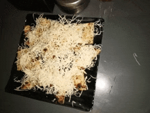 a black plate topped with bread and cheese is on a table