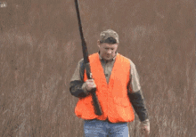 a man in an orange vest is holding a gun