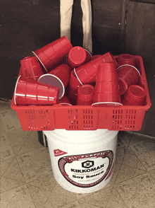 a bucket of kikkoman soy sauce sits next to a basket of red cups