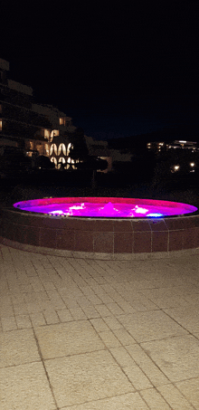 a hot tub is lit up at night with purple lights