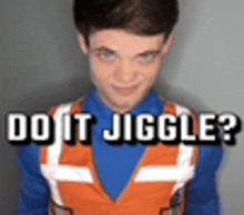 a young man wearing a blue shirt and an orange vest is standing in front of a sign that says do it jiggles ?