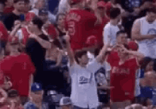 a crowd of people are watching a baseball game in a stadium and a boy is standing in the middle of the crowd .