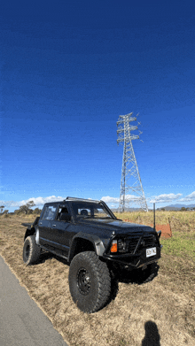 a black truck is parked on the side of a road with a power pole in the background