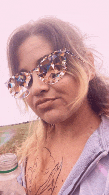 a woman with a tattoo on her chest wears sunglasses