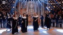 a group of nuns are dancing on a stage in front of a crowd with napoli written on the screen