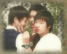 a group of young men are standing next to each other and one of them is eating a red apple .