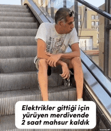 a man is sitting on a set of escalators with a caption that says elektrikler