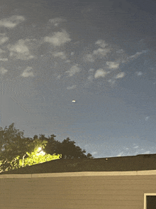 a house with a roof and a blue sky with clouds