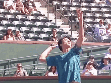 a man in a blue shirt is holding a tennis racquet in front of a stadium full of empty seats