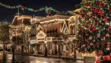 a christmas tree is sitting in front of a building decorated with christmas lights and decorations .