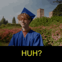 a young man in a blue graduation cap and gown is standing in front of a field of flowers with the words huh written in yellow