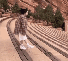 a woman in a plaid shirt and white shorts is walking down stairs .