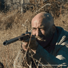 a bald man with a mustache is holding a rifle in a field with the butchers crossing movie written on the bottom