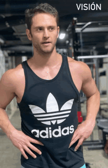 a man wearing a black tank top with the word adidas on it