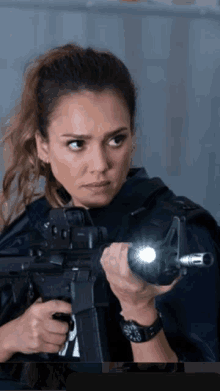 a woman is holding a gun with a flashlight attached to it