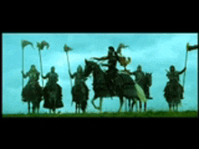 a group of men are riding horses in a field holding flags