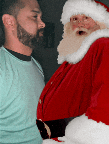 a man with a beard stands next to a santa claus