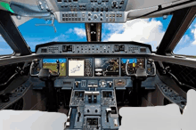 a cockpit of an airplane with a blue sky and clouds behind it