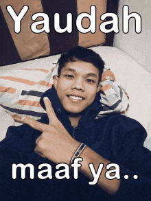 a young man laying on a bed with the words yaudah maaf ya on the bottom