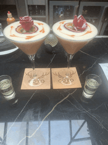 two martini glasses sitting on a table next to shot glasses with a deer on them