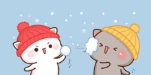 two cartoon cats wearing hats are playing with snow .