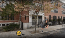 a woman is squatting down on the sidewalk in front of a building with a smiley face on it