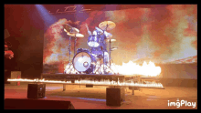 a drum set on a stage with flames coming out of it and the words imgplay below it