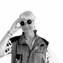 an older woman wearing sunglasses and a vest that says synchro