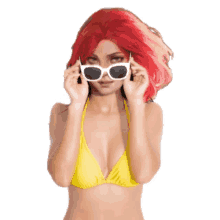 a woman with red hair wearing sunglasses and a yellow bikini top