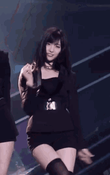 a woman in a black dress is dancing on stage .