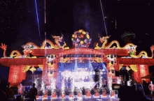 fireworks are being displayed in front of a stage with a dragon on top