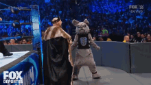 a fox deportes broadcast of a wrestling match with a mascot in the ring