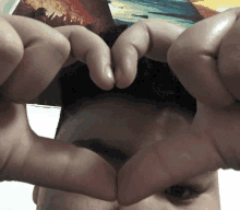 a person making a heart shape with their fingers