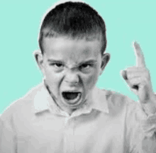 a young boy is making a funny face and pointing his finger up .