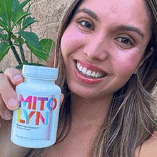 a woman is smiling while holding a bottle of mito lynn .