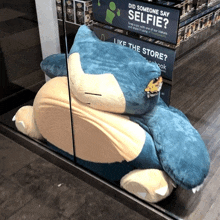 a large stuffed animal is laying in front of a sign that says did someone say selfie