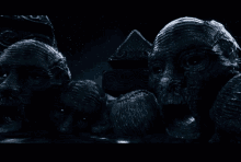 a statue of a man with a beard is surrounded by other statues in a dark room