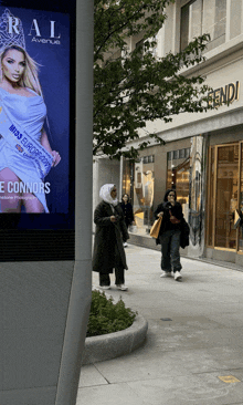 a woman wearing a hijab walks past a miss europe sign