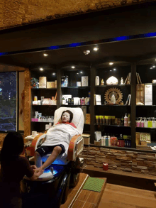 a woman with a mask on her face sits in a chair at a spa