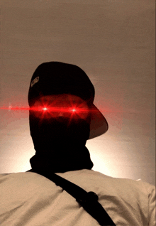 a man wearing a mask and a hat has red lights coming out his eyes