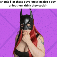 a woman with red hair is wearing a batman mask and has a tattoo on her arm