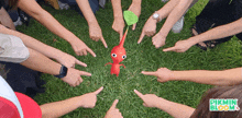 a group of people pointing at a red pikmin in the middle