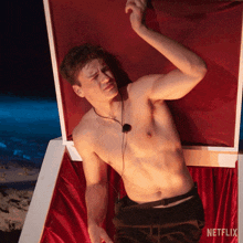 a shirtless man is laying in a box that says netflix on the bottom