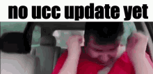 a man is sitting in the back seat of a car with his hands on his head and the words no ucc update yet above him .