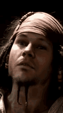 a close up of a man wearing a bandana and a beard .