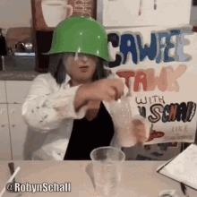 a woman wearing a green hard hat sits at a table in front of a sign that says caweel talk