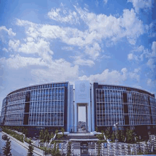 a large building with a blue sky and clouds in the background